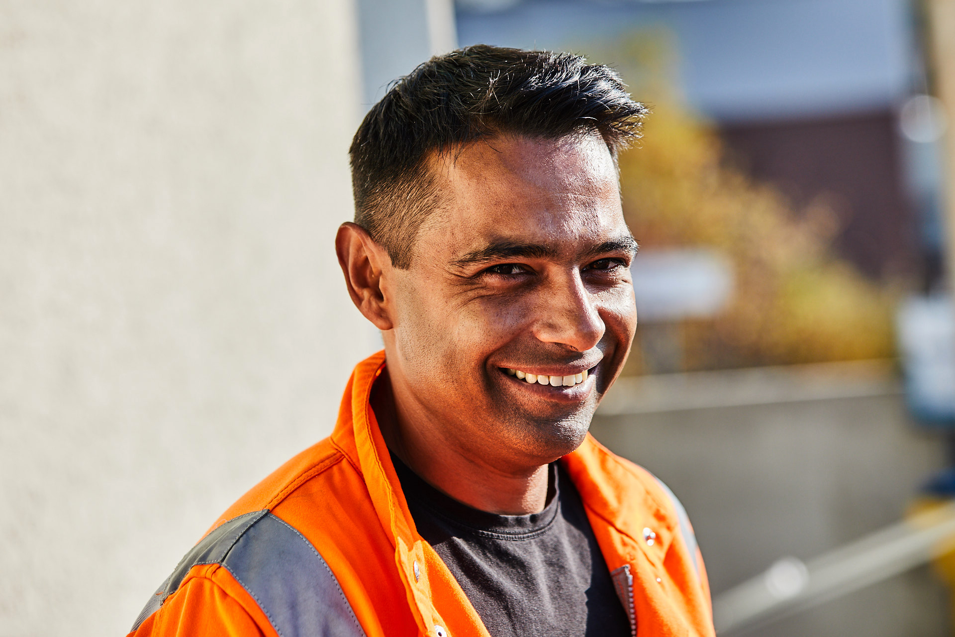 Portraitfoto von Arton Kadrija. Er trägt eine orange Warnjacke und lächelt. (&copy; )