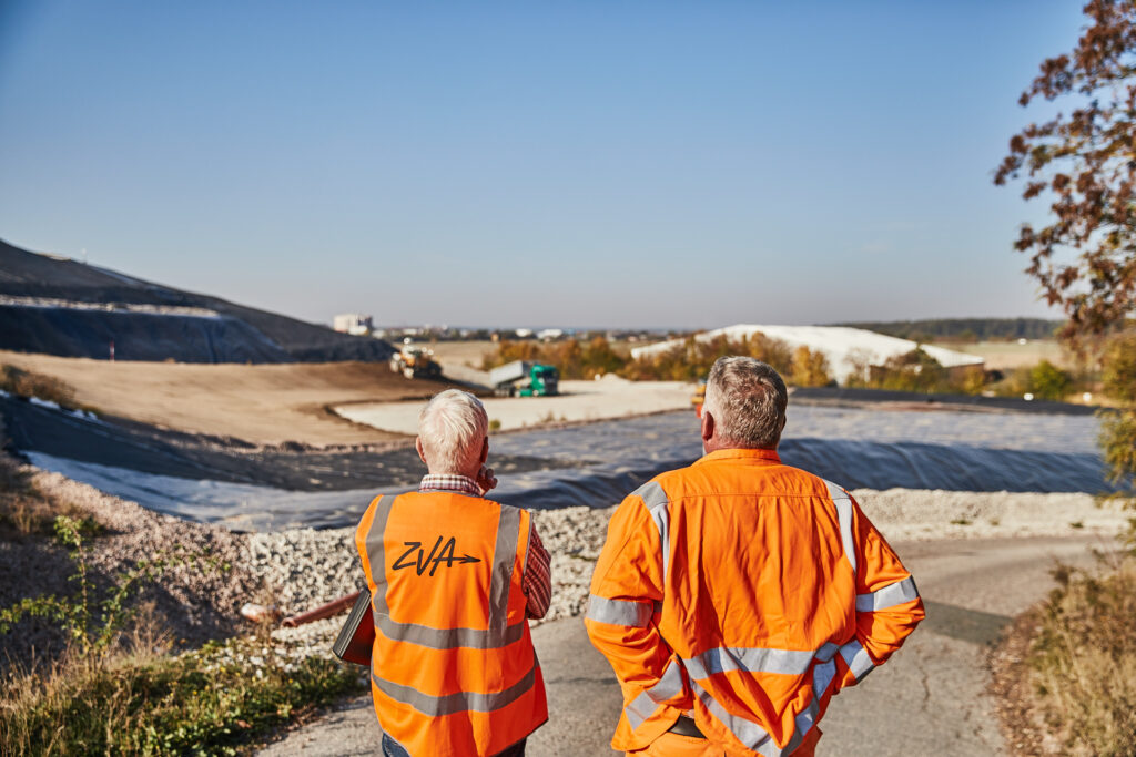 Zwei Mitarbeiter schaue auf die Aufschüttung der Deponie Herzogenaurach.