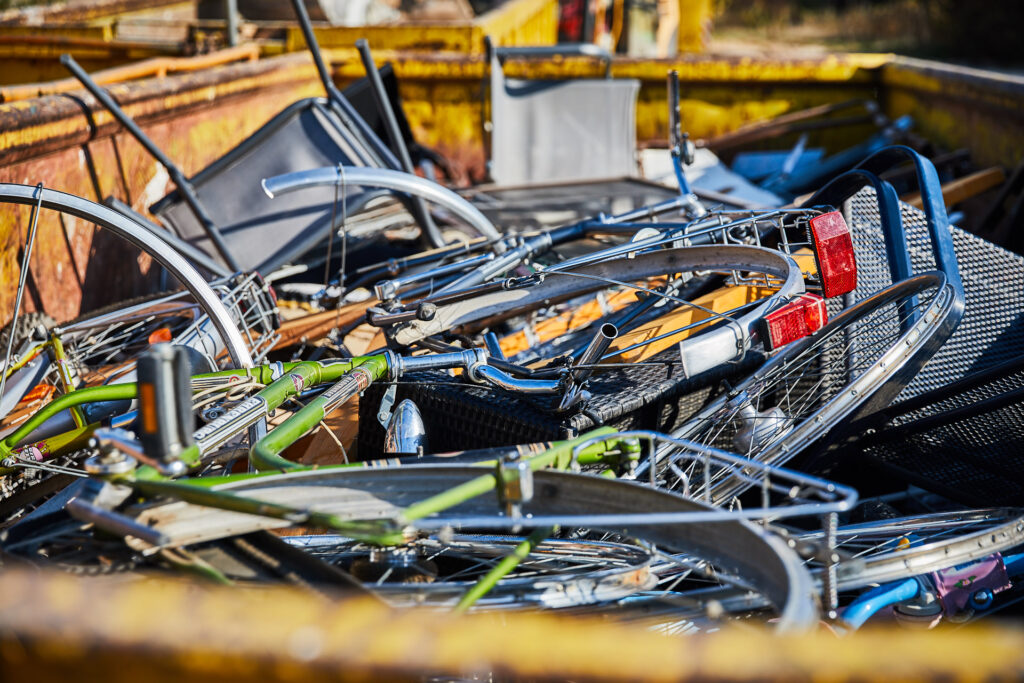 Alte Fahrräder liegen in einem Container.